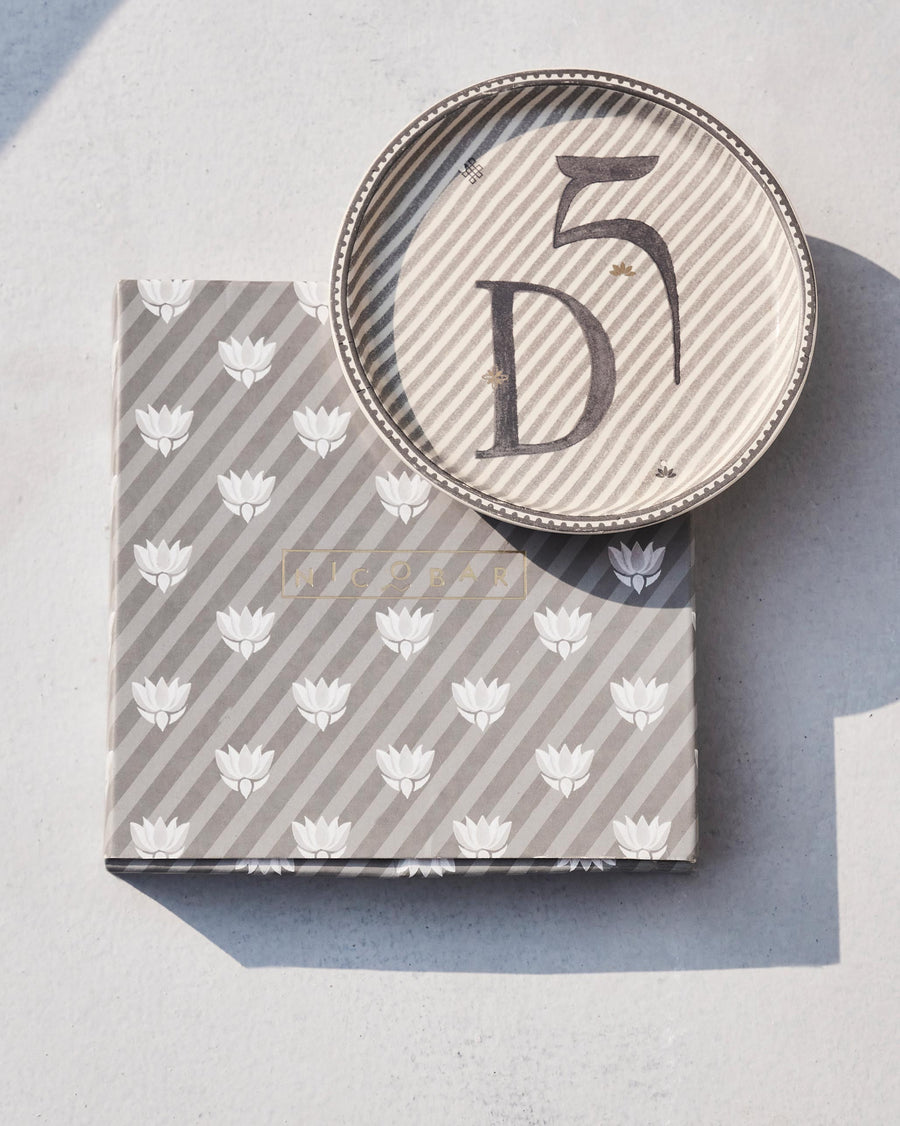 The Akshar Coaster beside its striped gift box.