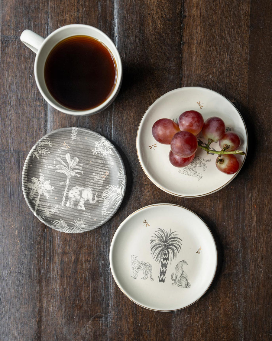 Periyar plates with grapes beside a mug of black coffee on dark wood