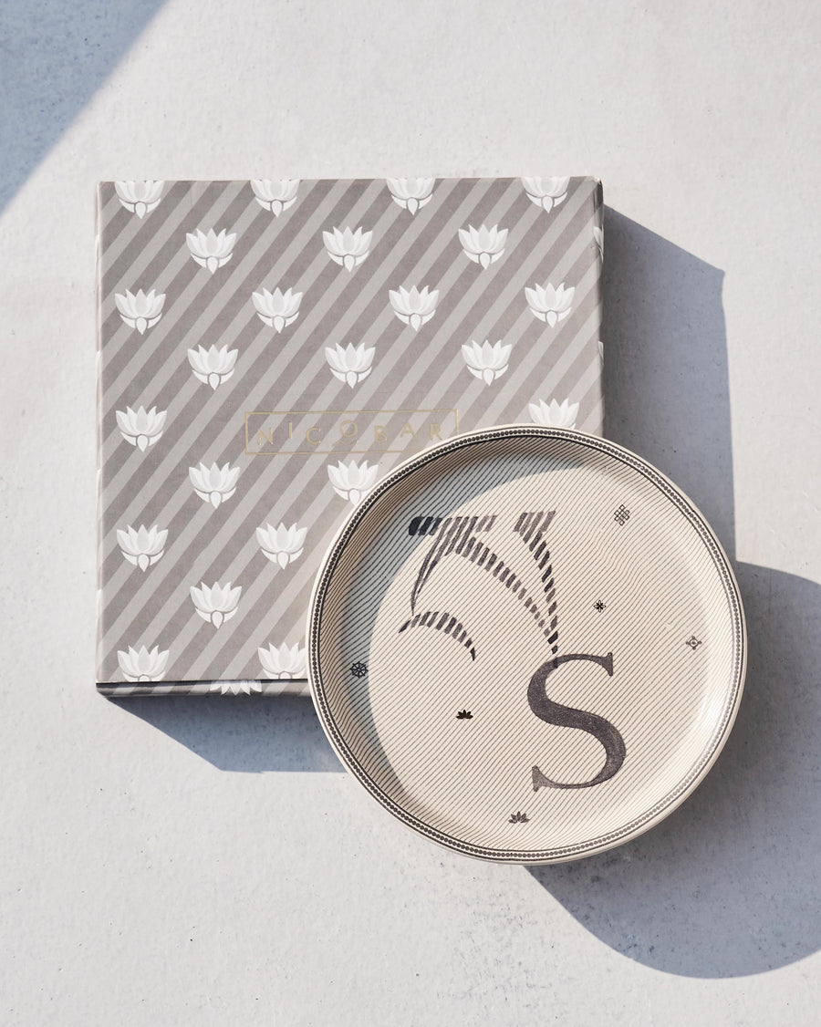 The Akshar Coaster beside its striped gift box.