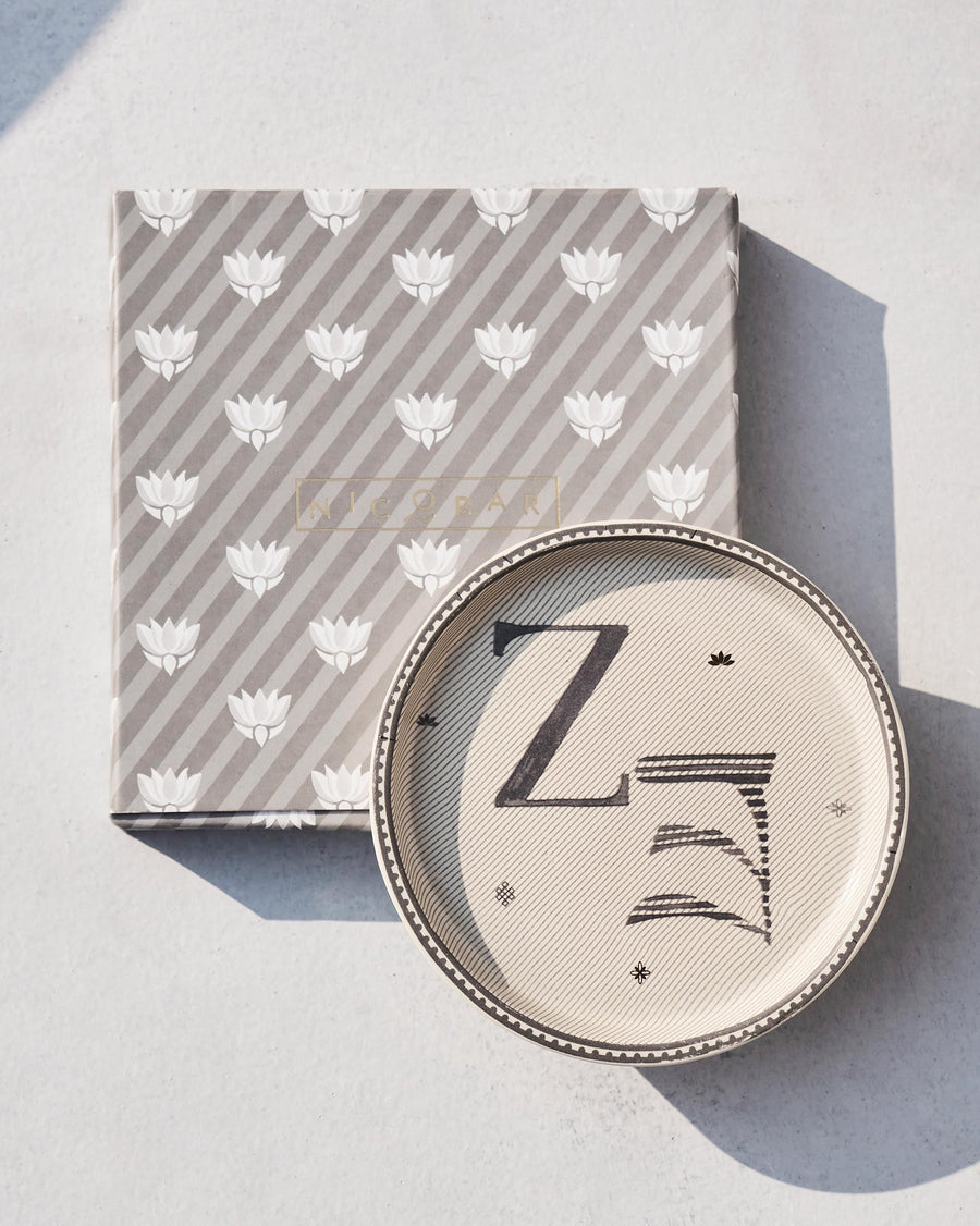 The Akshar Coaster beside its striped gift box.