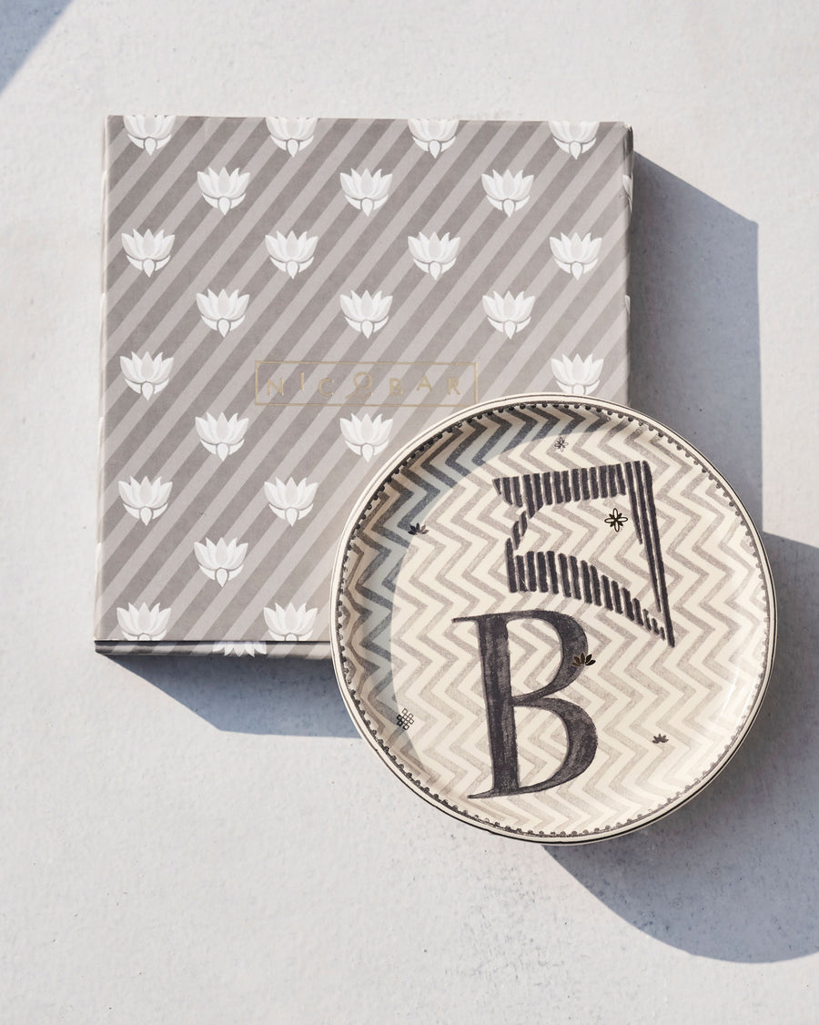 The Akshar Coaster beside its striped gift box.