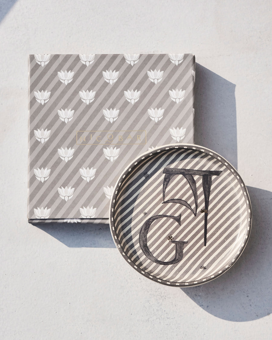 The Akshar Coaster beside its striped gift box.