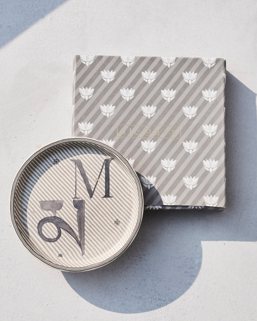 The Akshar Coaster beside its striped gift box.