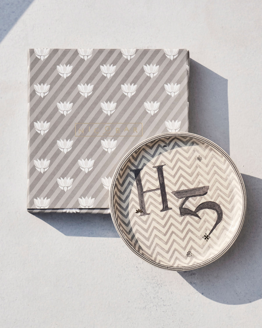 The Akshar Coaster beside its striped gift box.