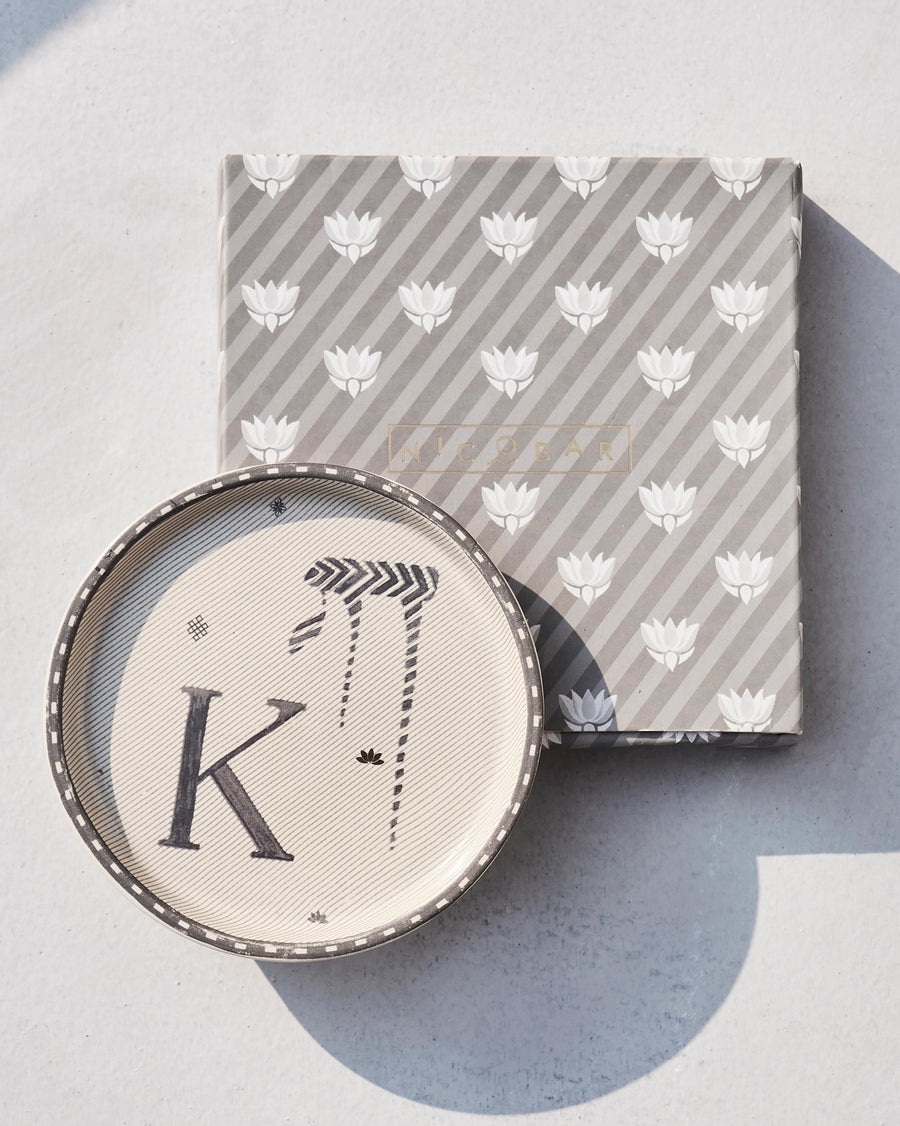 The Akshar Coaster beside its striped gift box.