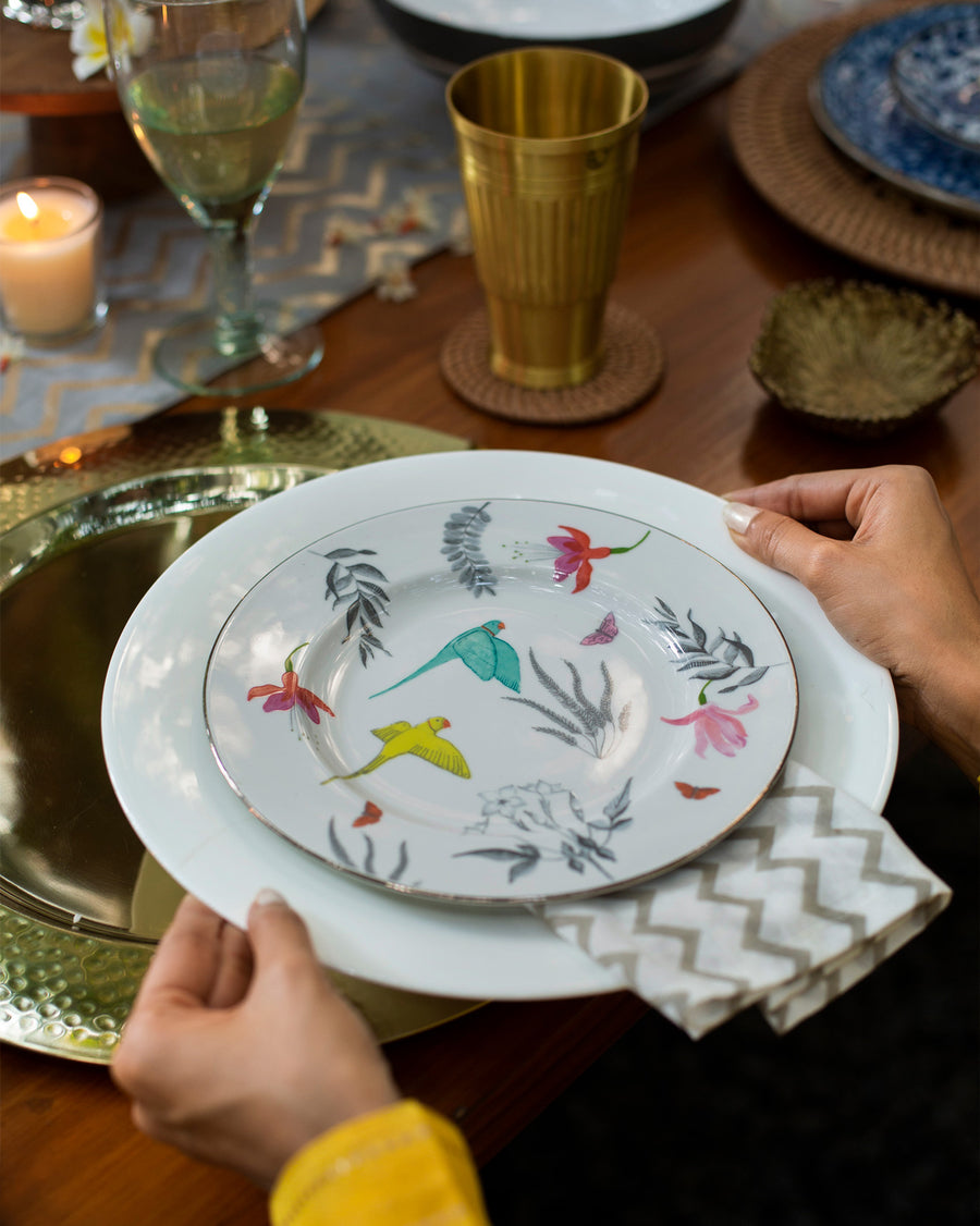 Hands setting a Botanical quarter plate on a gold charger at a festive table