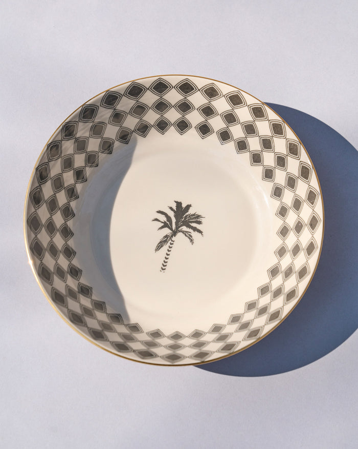 Overhead view of an Oasis shallow bowl with a palm motif and diamond border.