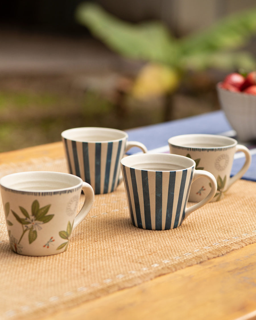 Four Nadi mugs, two striped and two with leaves, on a jute mat outdoors
