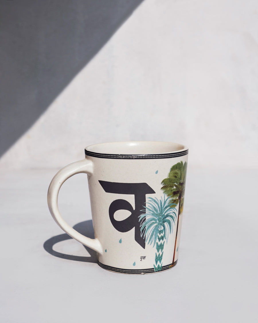 The Vriksh Mug side-on, printed with व and palm trees.