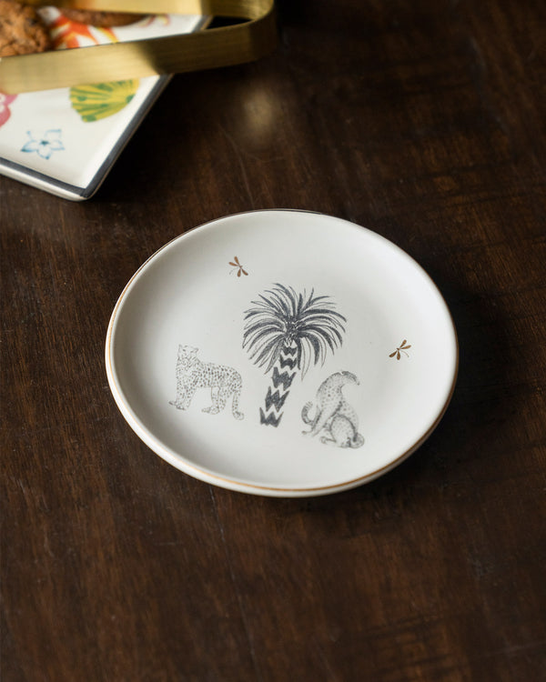 A white plate with a grey palm, a leopard and a seated monkey