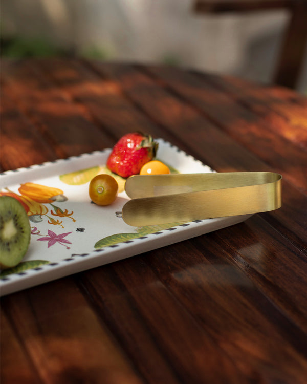Close view of the gold tongs over fruit