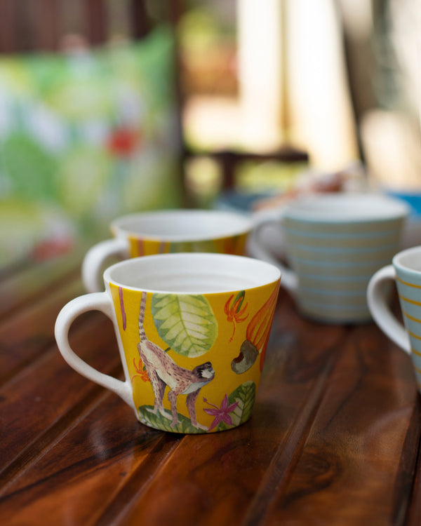 A yellow mug with a monkey and cashew illustration
